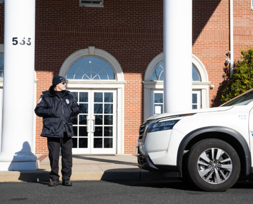 Front View Of Police Officer Looking At Cop Car